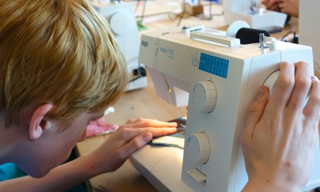 Schüler näht an der Nähmaschine