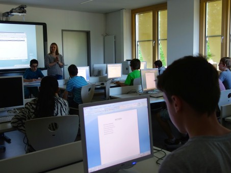 Schüler der Klassen 7 sitzen an PCs und lassen sich mit dem Beamer eine Präsentation zeigen.