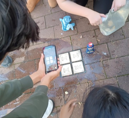Schüler reinigen Stolpersteine und filmen dabei