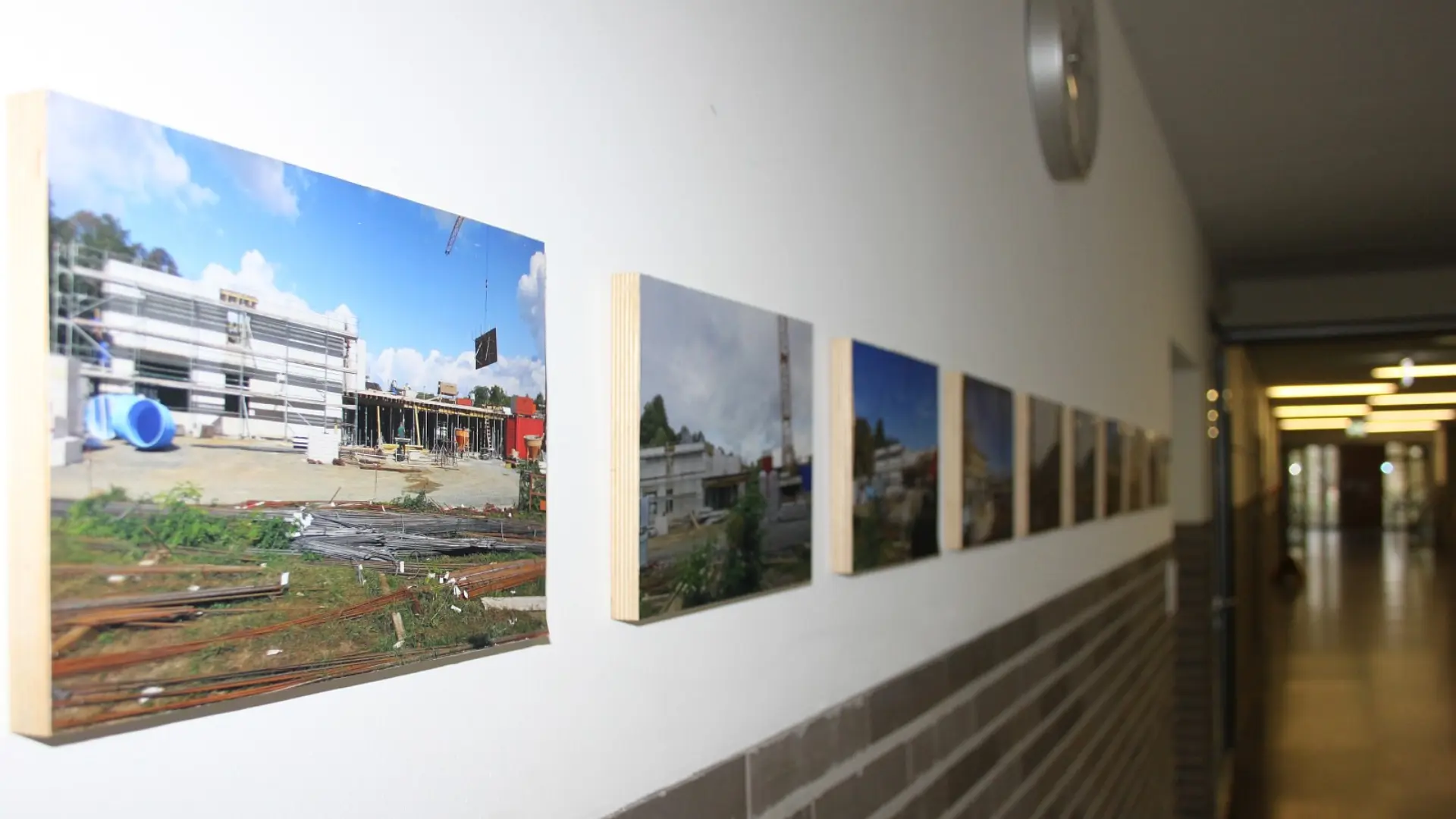 Fotogalerie im Flur der Ernst-Jandl-Schule, die die verschiedenen Stadien des Schulneubaus und der Baugeschichte zeigt.