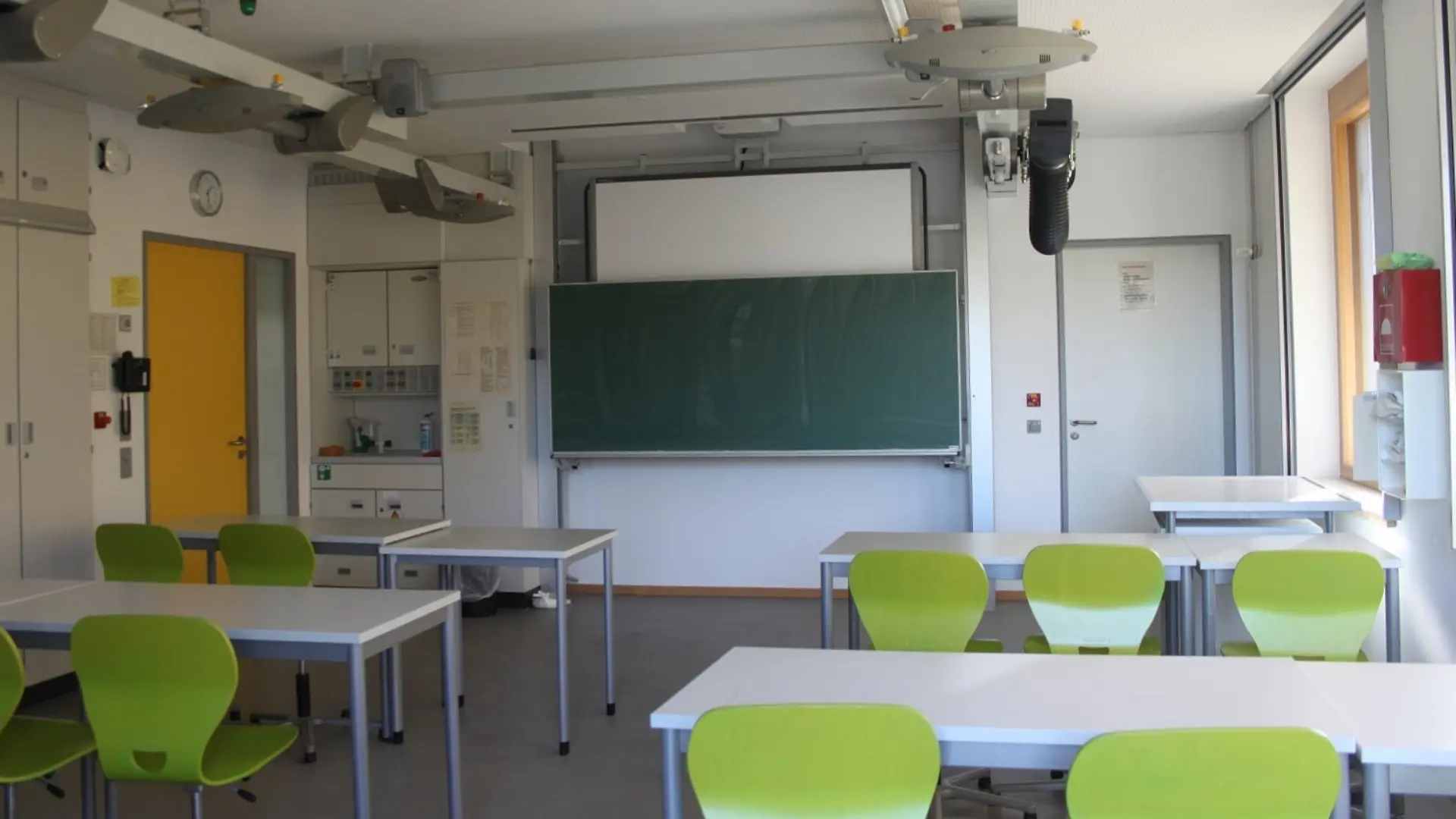Ein modern eingerichtetes Klassenzimmer der LVR-Ernst-Jandl-Schule mit grünen Stühlen, digitalen Projektionsmöglichkeiten und funktionaler Deckentechnik.